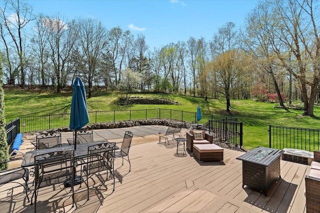 wooden terrace featuring a lawn, fence, and outdoor dining area