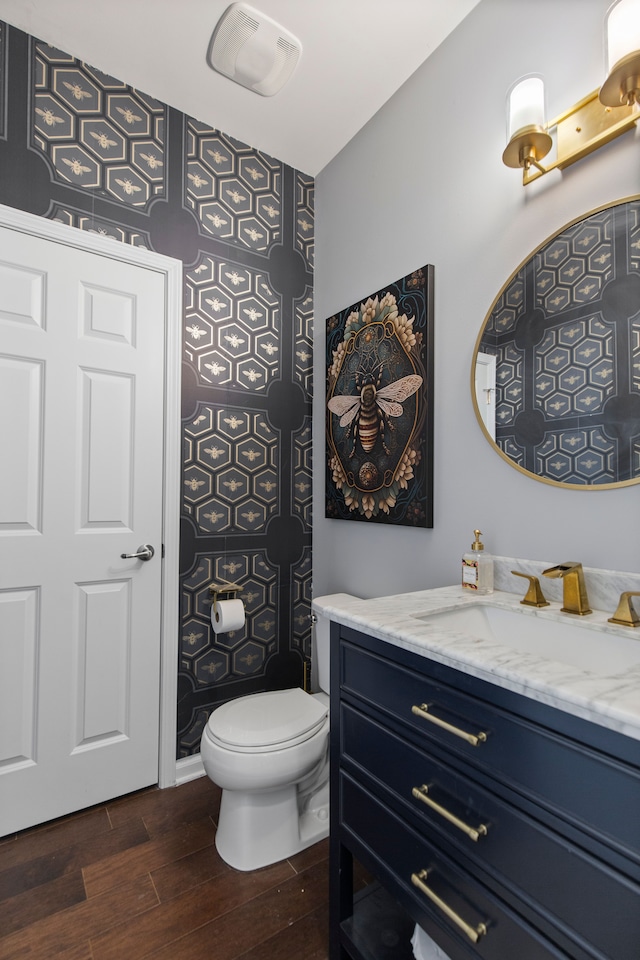 bathroom with vanity, toilet, wood finished floors, and visible vents