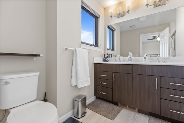 bathroom with double vanity, toilet, baseboards, and a sink