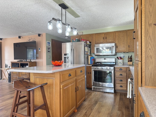 kitchen with dark wood-style flooring, light countertops, a textured ceiling, brown cabinets, and appliances with stainless steel finishes
