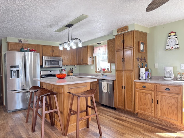 kitchen with appliances with stainless steel finishes, brown cabinetry, and a textured ceiling