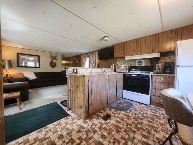 1837 9 Mile Rd, Sears, MI 49679 - kitchen with white appliances, under cabinet range hood, a peninsula, open floor plan, and brown cabinetry