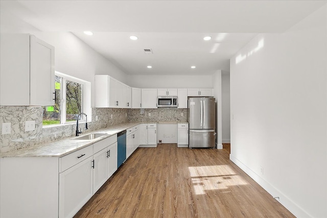 494 Bloomfield Ave, Pontiac, MI 48341 - kitchen with white cabinets, tasteful backsplash, a sink, light wood-style flooring, and stainless steel appliances