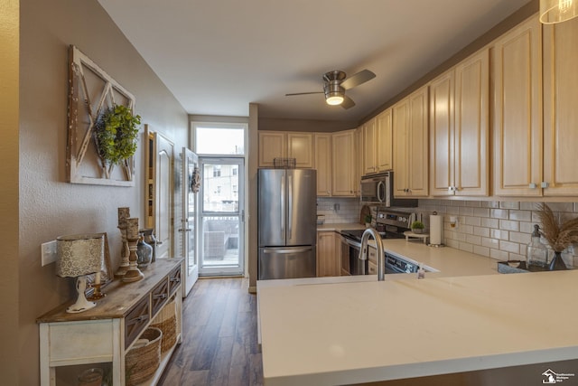 kitchen featuring a ceiling fan, backsplash, dark wood finished floors, light countertops, and stainless steel appliances