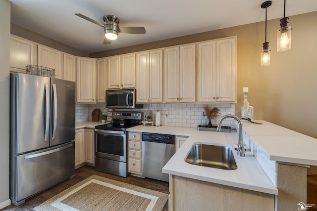 kitchen featuring a sink, a peninsula, a ceiling fan, backsplash, and stainless steel appliances