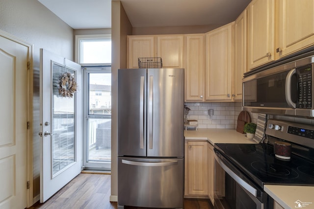 kitchen with decorative backsplash, light brown cabinetry, wood finished floors, light countertops, and stainless steel appliances