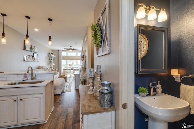 interior space featuring ceiling fan, two sinks, a textured wall, and wood finished floors