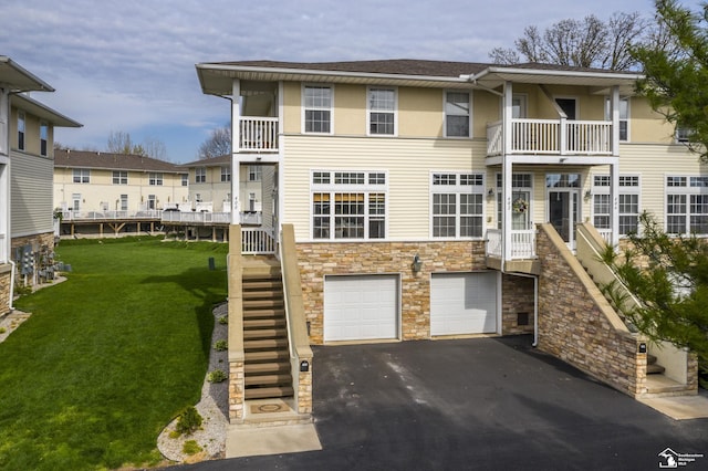view of front of property with driveway, a front lawn, an attached garage, stairs, and stone siding
