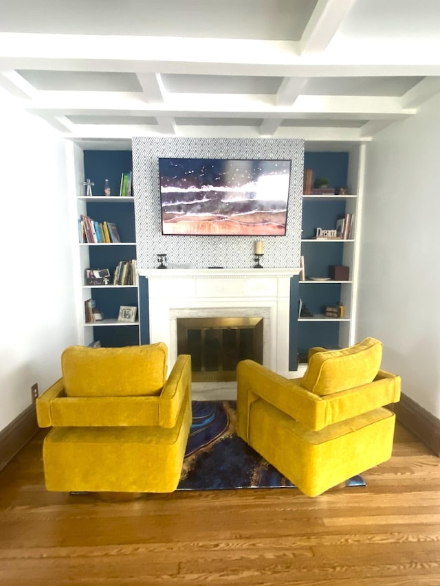 sitting room with beam ceiling, baseboards, a fireplace, and wood finished floors