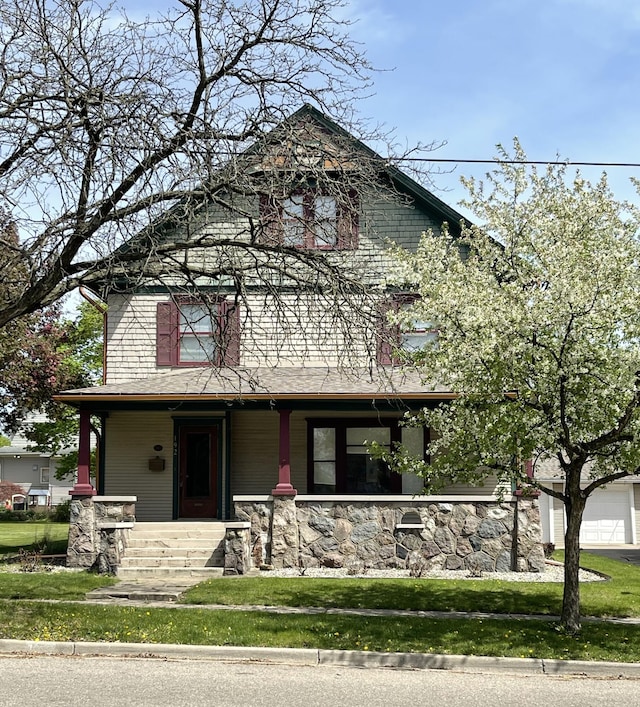 view of front of property featuring a porch, a front lawn, and stone siding