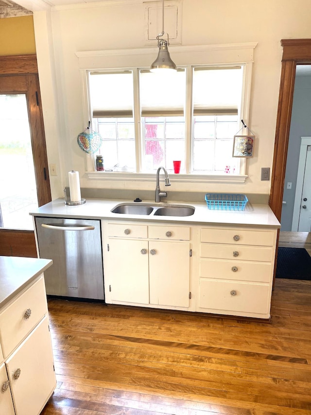 kitchen with stainless steel dishwasher, dark wood finished floors, a sink, and light countertops