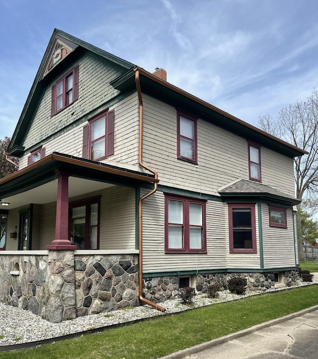 view of side of home featuring covered porch and a chimney