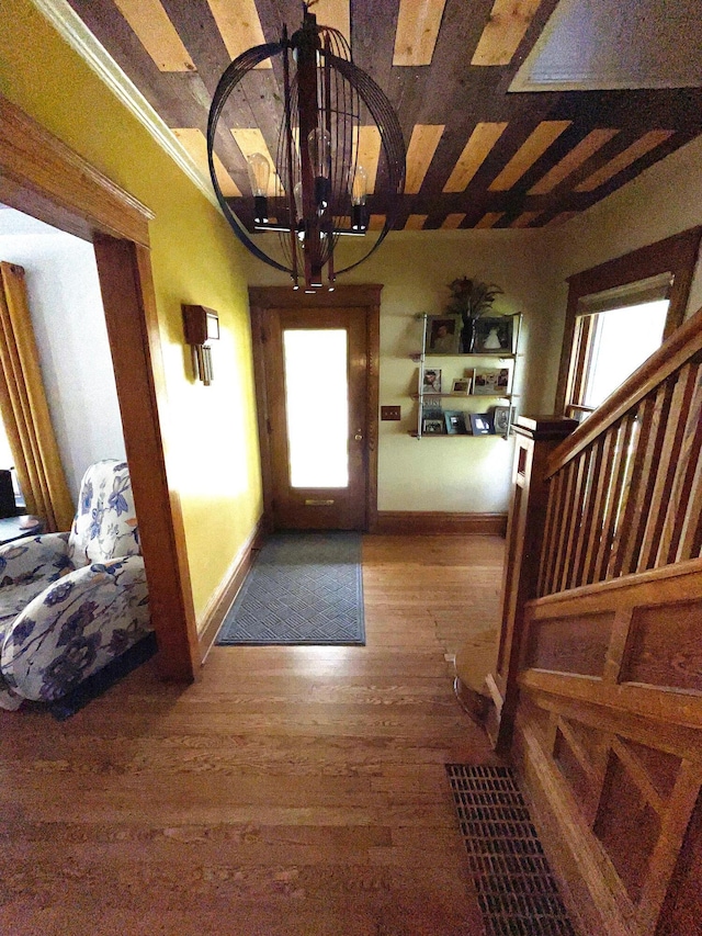 entryway featuring baseboards, plenty of natural light, wood finished floors, and a notable chandelier