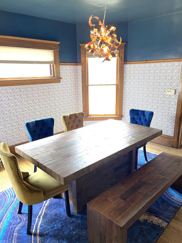dining space with wainscoting, wood finished floors, and a notable chandelier