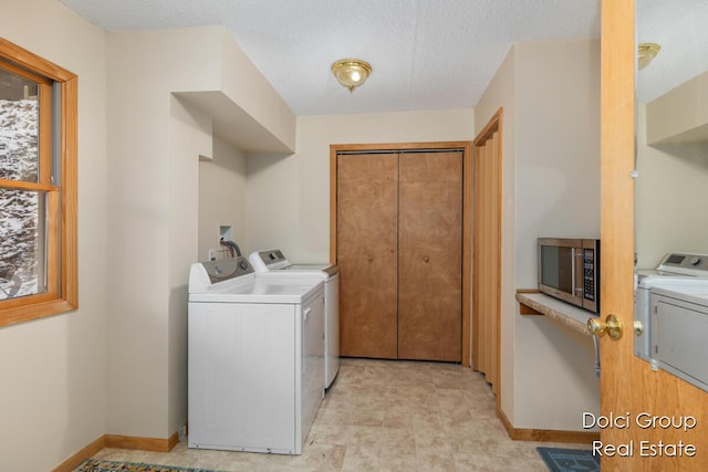 laundry room featuring baseboards, laundry area, a textured ceiling, and independent washer and dryer