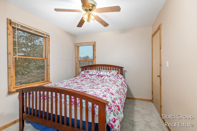 carpeted bedroom with a ceiling fan, baseboards, and multiple windows