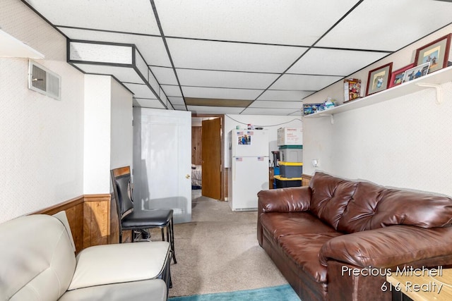 living area featuring a wainscoted wall, carpet, a paneled ceiling, and visible vents