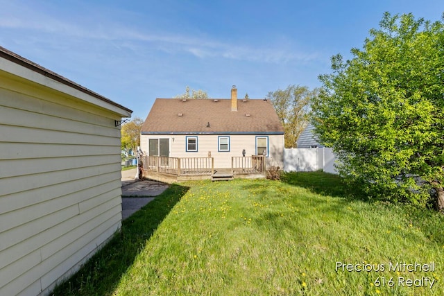 rear view of house featuring a lawn, fence, and a deck