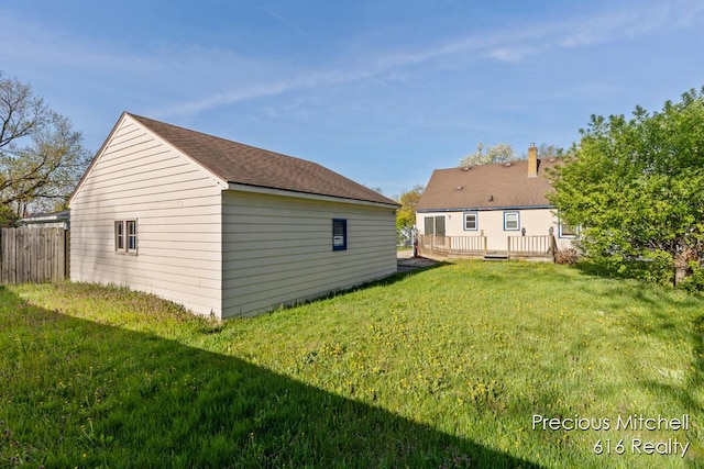 back of property with fence, a wooden deck, and a yard