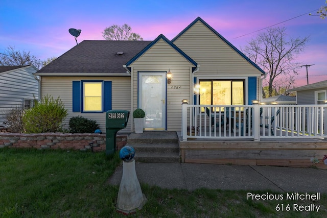 bungalow with roof with shingles and a wooden deck