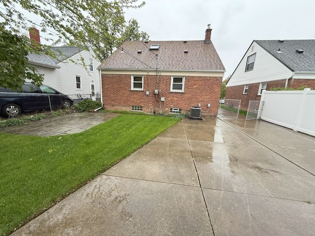 rear view of property with a yard, fence, a chimney, and brick siding