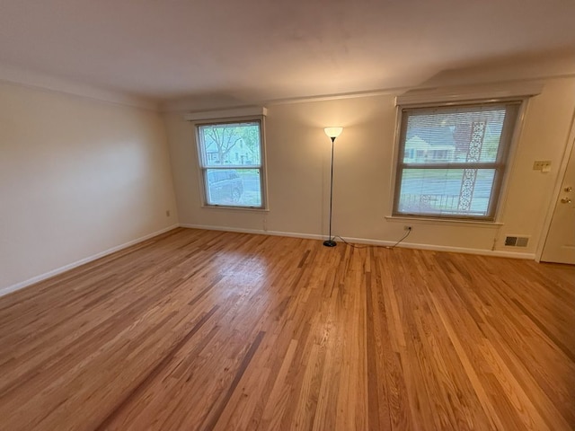 unfurnished room featuring visible vents, light wood-style flooring, and baseboards
