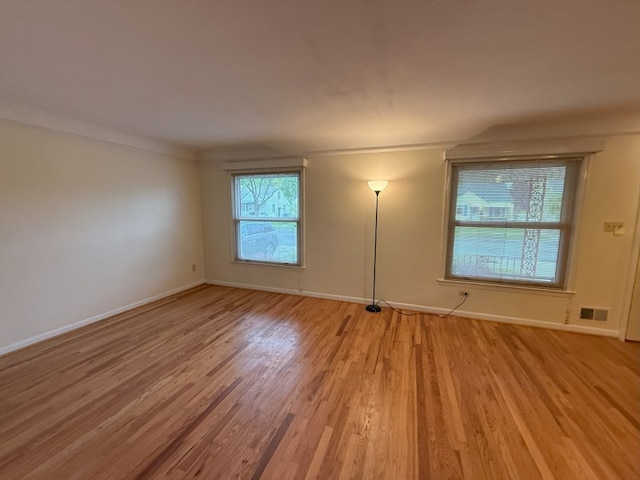 spare room with baseboards, light wood-style floors, and visible vents