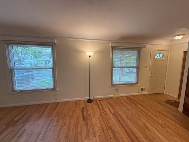 entrance foyer with light wood-type flooring, visible vents, baseboards, and ornamental molding