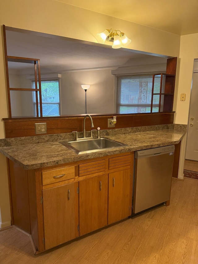 kitchen featuring dishwasher, brown cabinetry, a sink, dark countertops, and light wood-type flooring