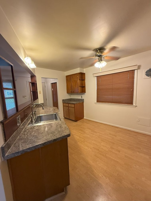 kitchen with brown cabinetry, ceiling fan, a sink, open shelves, and dark countertops
