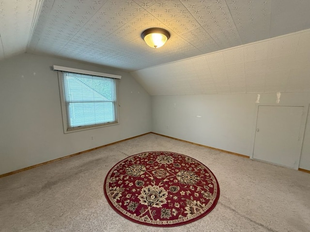 additional living space featuring baseboards, light carpet, and vaulted ceiling