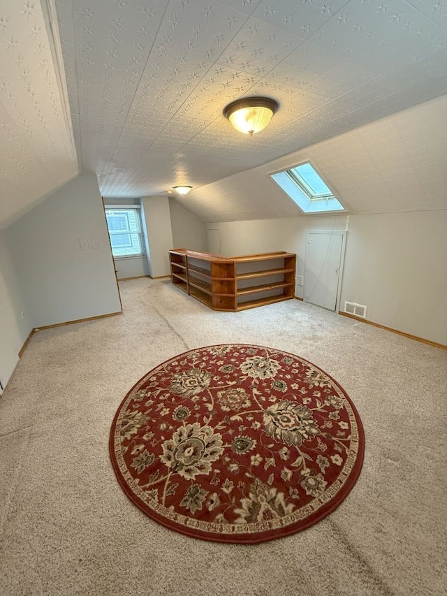 additional living space with carpet, visible vents, and lofted ceiling with skylight