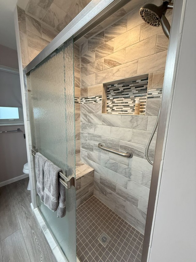 full bath featuring a stall shower, toilet, and wood finished floors
