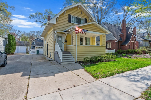 bungalow-style home featuring a chimney, a front yard, a residential view, a garage, and an outdoor structure