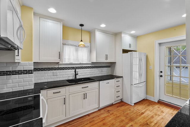 kitchen with white appliances, hanging light fixtures, decorative backsplash, and a sink