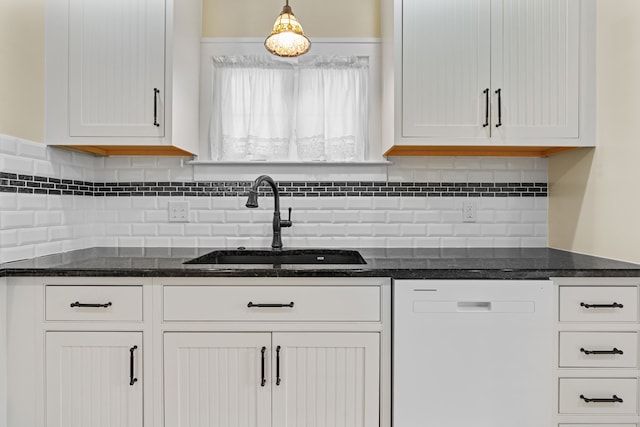 kitchen with white dishwasher, white cabinets, and a sink