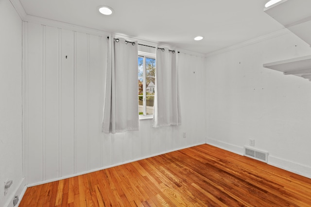empty room with visible vents, ornamental molding, baseboards, and wood finished floors