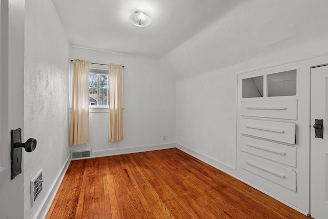 spare room with baseboards, wood finished floors, and visible vents