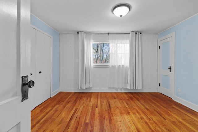 spare room with baseboards and wood finished floors