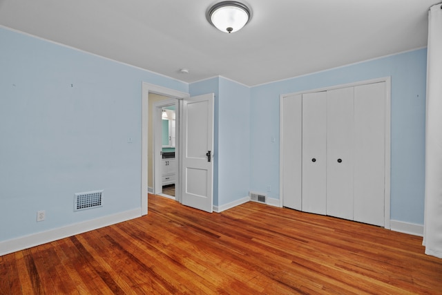 unfurnished bedroom featuring baseboards, visible vents, and wood finished floors