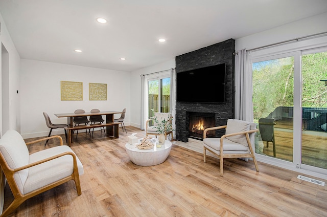 living area featuring visible vents, recessed lighting, light wood-style floors, and a large fireplace