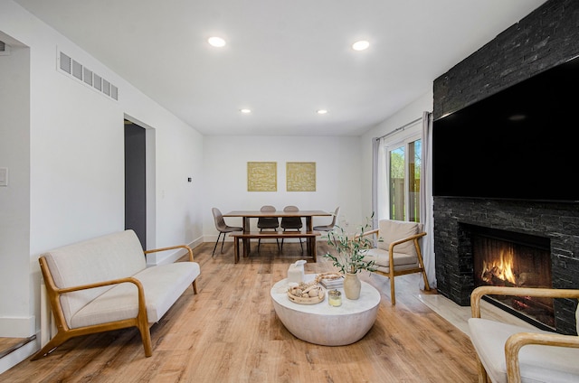 living area featuring a fireplace, recessed lighting, visible vents, and light wood-style floors