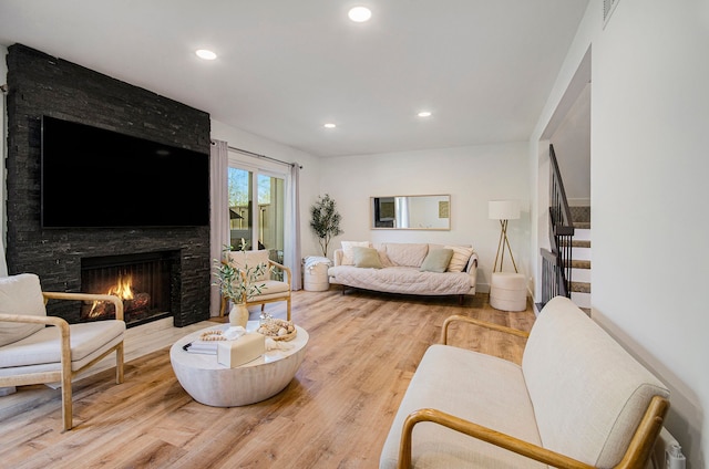 living room with a fireplace, recessed lighting, stairway, and light wood-type flooring