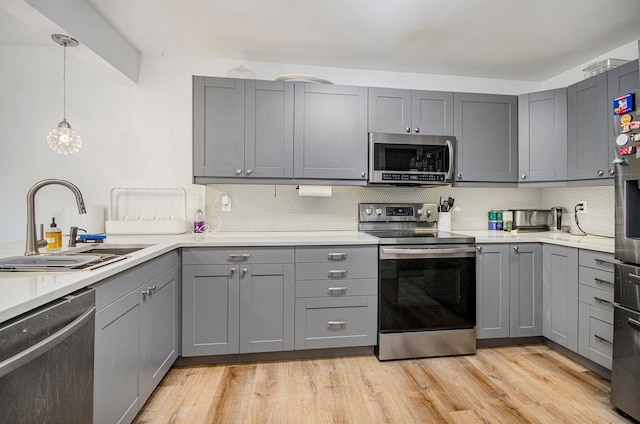 kitchen featuring gray cabinetry, decorative backsplash, stainless steel appliances, and a sink
