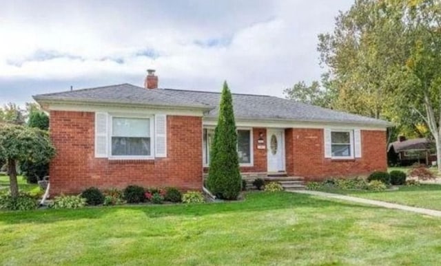 single story home with brick siding, a front lawn, and a chimney