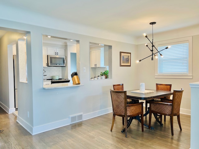 dining room featuring baseboards, visible vents, an inviting chandelier, and wood finished floors