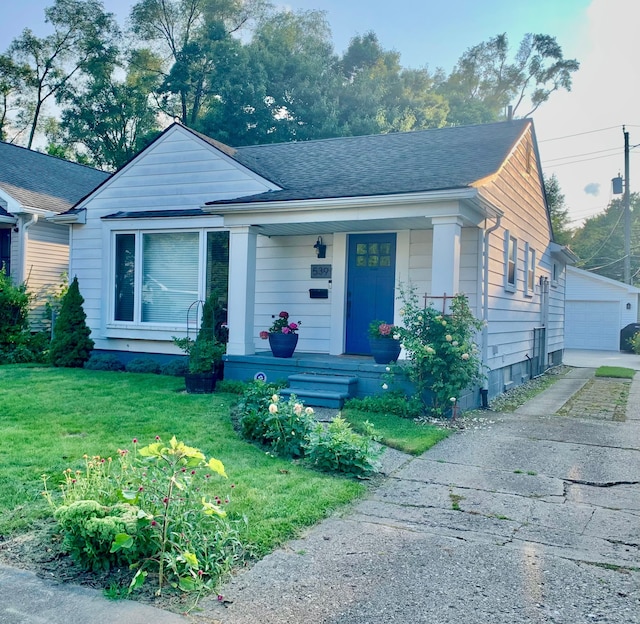 bungalow with a porch, a front yard, a detached garage, an outdoor structure, and a shingled roof