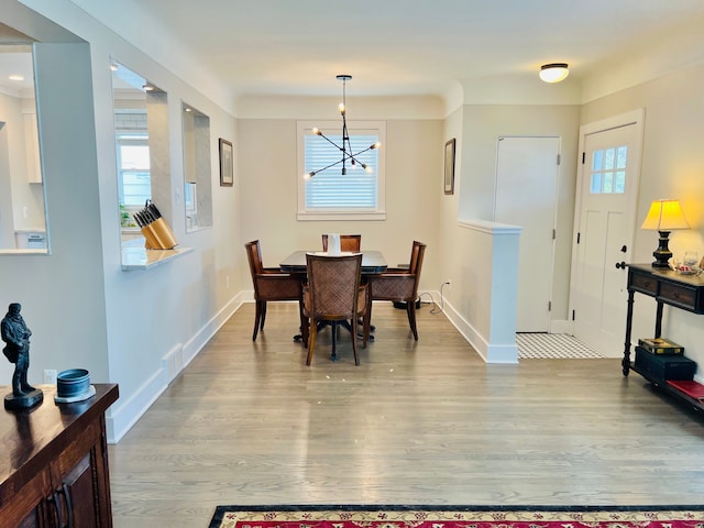 dining area featuring baseboards, wood finished floors, and a notable chandelier
