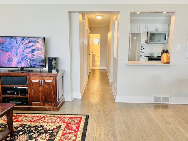 living area featuring visible vents, baseboards, and wood finished floors