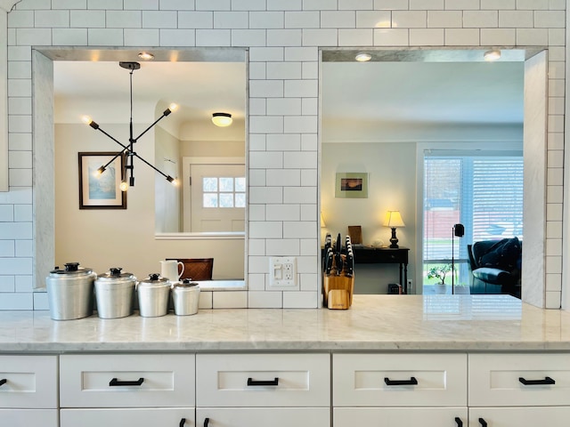 kitchen with a healthy amount of sunlight, light stone counters, and white cabinets
